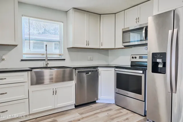 a kitchen with stainless steel appliances granite countertop white cabinets a microwave a sink and a refrigerator