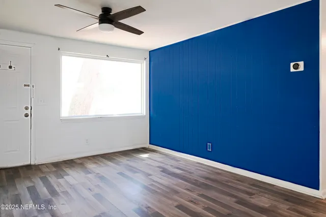 an empty room with wooden floor closet and windows
