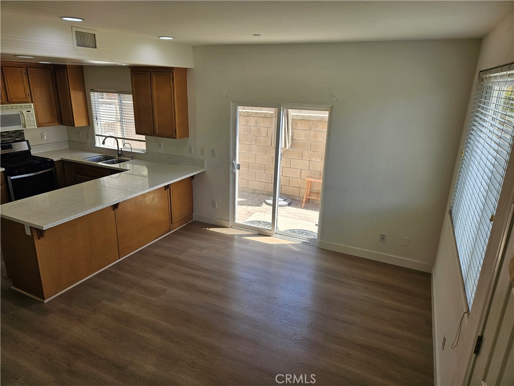 8598 Belmont Street Cypress, CA 90630 - Photo 7 of 23 a large kitchen with stainless steel appliances a large counter top a wooden floor and a sink