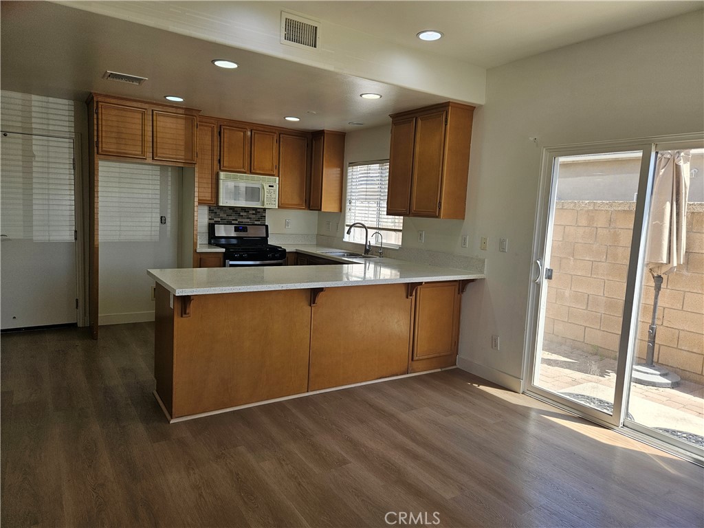 8598 Belmont Street Cypress, CA 90630 - Photo 10 of 23 a kitchen with kitchen island granite countertop wooden cabinets a sink a refrigerator and a stove