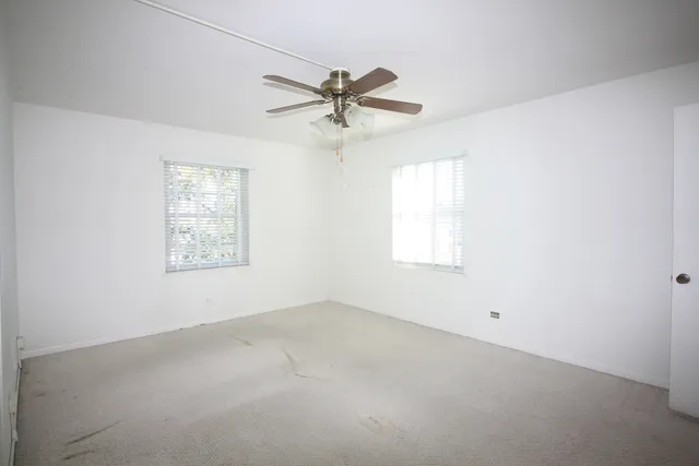 an empty room with windows and fan