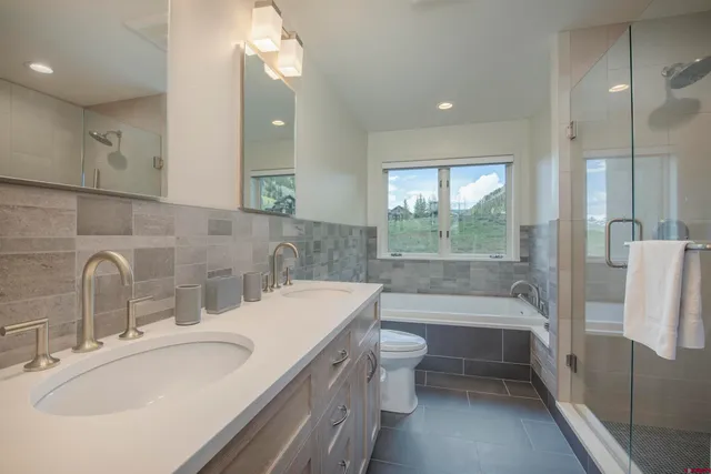 a bathroom with a bathtub sink vanity mirror and toilet