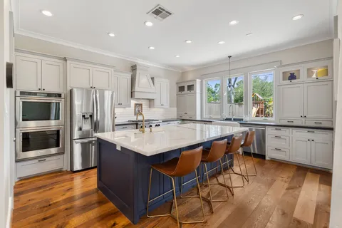 a large white kitchen with stainless steel appliances granite countertop a lot of counter space and a large window