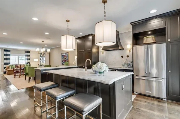 a kitchen with stainless steel appliances kitchen island granite countertop a table chairs and a refrigerator