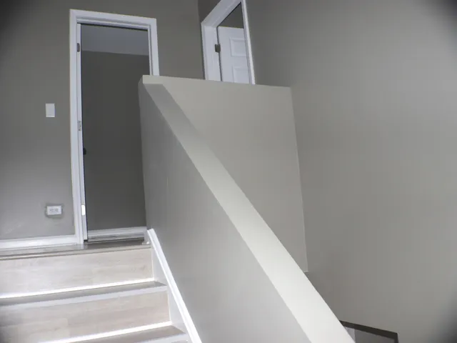 a view of staircase with white walls and white door