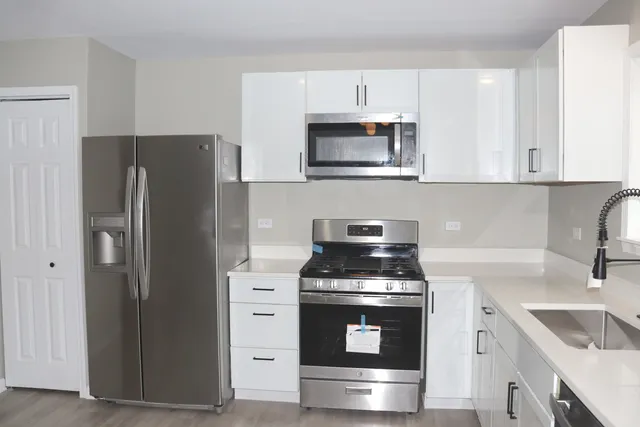 a kitchen with white cabinets and stainless steel appliances