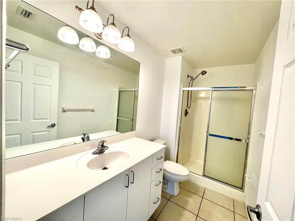 5470 16th Place Southwest, Unit 107 Naples, FL 34116 - Photo 19 of 31 a bathroom with a sink a toilet and shower a mirror