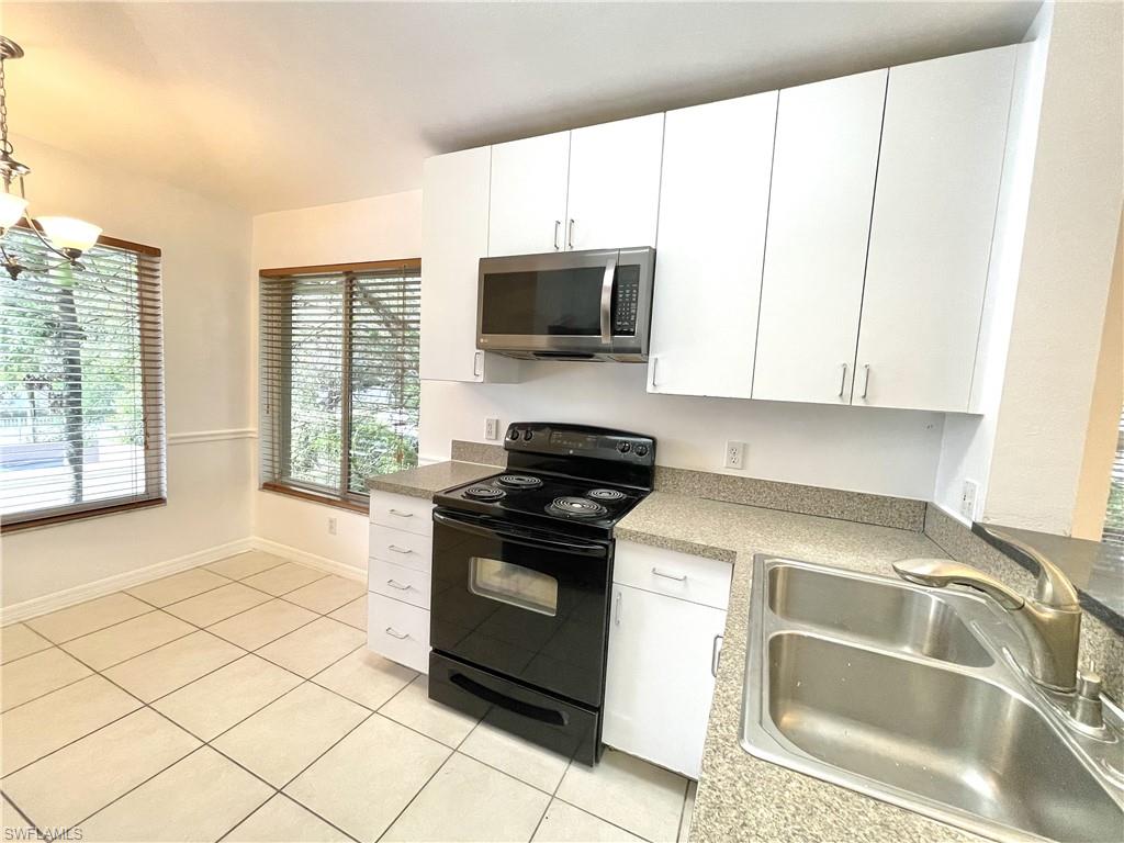 5470 16th Place Southwest, Unit 107 Naples, FL 34116 - Photo 5 of 31 a kitchen with granite countertop a sink and a stove top oven