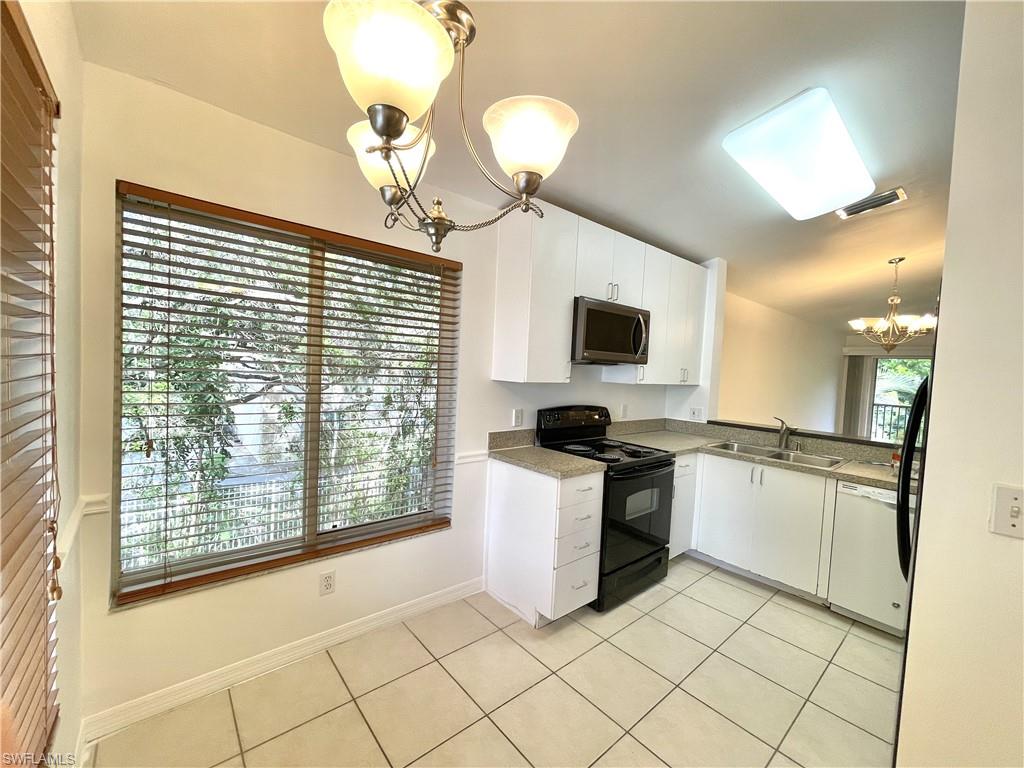 5470 16th Place Southwest, Unit 107 Naples, FL 34116 - Photo 6 of 31 a kitchen with a stove a sink and a refrigerator