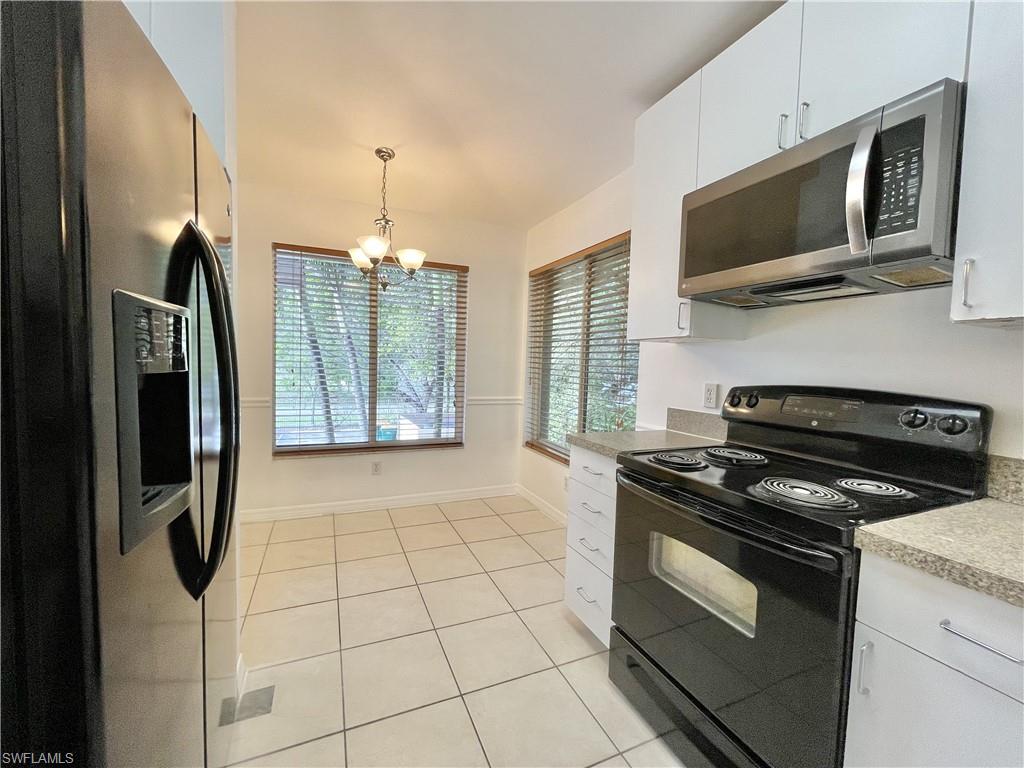 5470 16th Place Southwest, Unit 107 Naples, FL 34116 - Photo 8 of 31 a kitchen with a stove a microwave and refrigerator