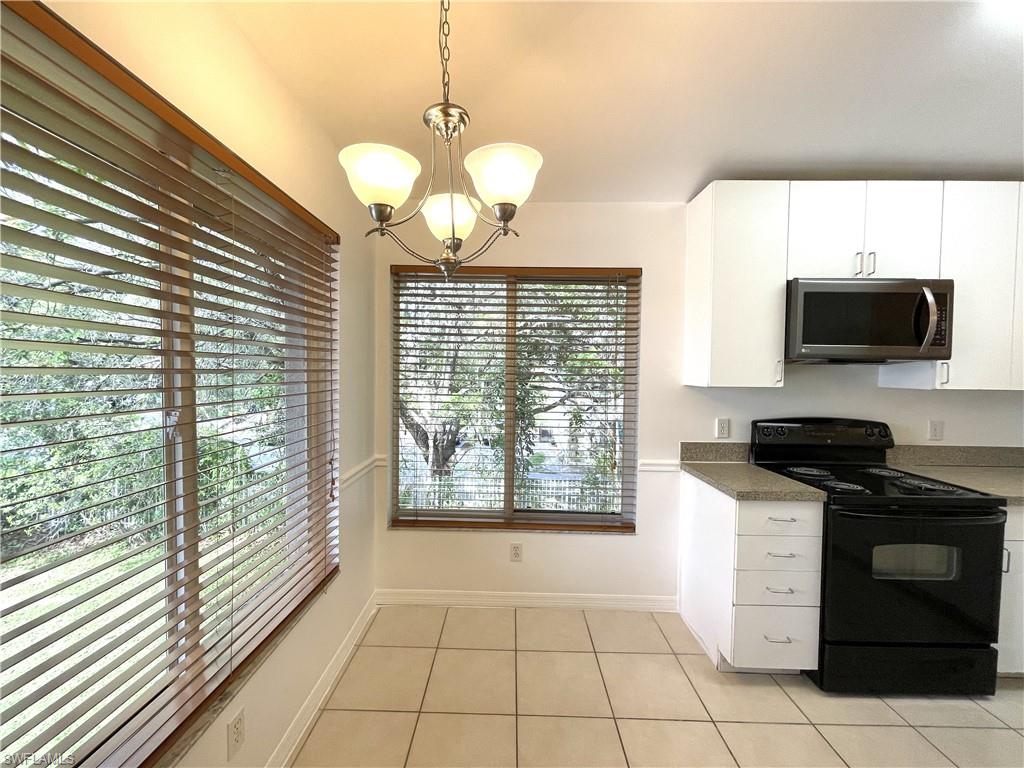 5470 16th Place Southwest, Unit 107 Naples, FL 34116 - Photo 9 of 31 a kitchen with stainless steel appliances granite countertop a stove a sink and a microwave