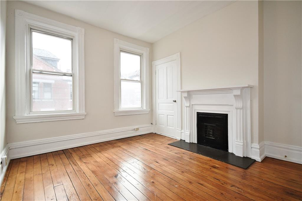 4627 Plummer Street Pittsburgh, PA 15201 - Photo 16 of 29 an empty room with wooden floor fireplace and windows