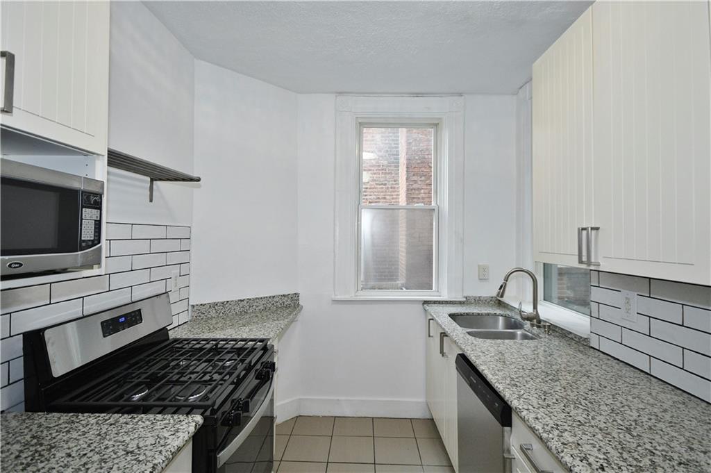 4627 Plummer Street Pittsburgh, PA 15201 - Photo 5 of 29 a kitchen with granite countertop a sink stove and cabinets