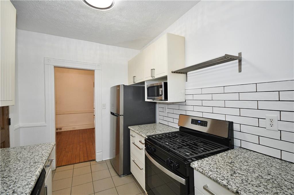 4627 Plummer Street Pittsburgh, PA 15201 - Photo 6 of 29 a kitchen with granite countertop a stove and a refrigerator