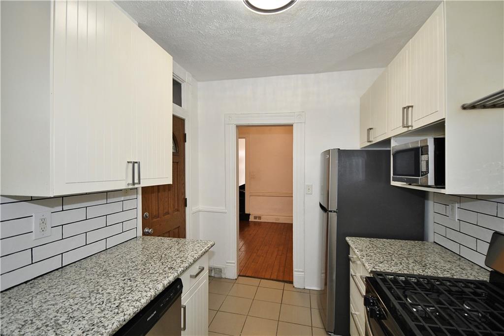 4627 Plummer Street Pittsburgh, PA 15201 - Photo 8 of 29 a kitchen with stainless steel appliances granite countertop a refrigerator and a stove