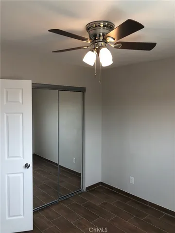 an empty room with wooden floor chandelier fan and windows