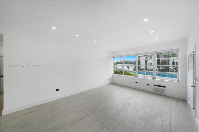 a view of an empty room with wooden floor and windows