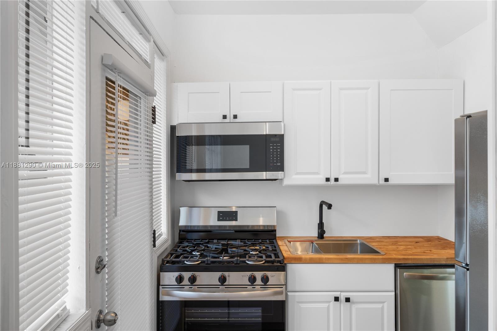 4710 Pine Tree Drive, Unit 31 Miami Beach, FL 33140 - Photo 19 of 25 a kitchen with stainless steel appliances granite countertop a stove a sink and a white cabinets