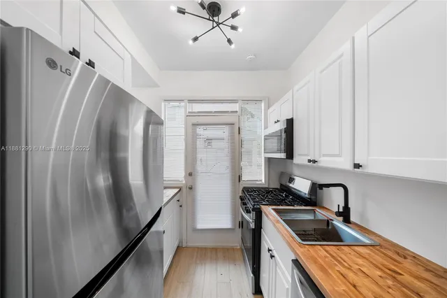 a kitchen with stainless steel appliances granite countertop a refrigerator a sink dishwasher a stove and white countertops with wooden floor