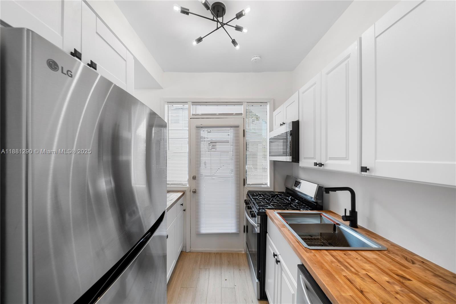 4710 Pine Tree Drive, Unit 31 Miami Beach, FL 33140 - Photo 5 of 25 a kitchen with stainless steel appliances granite countertop a refrigerator a sink dishwasher a stove and white countertops with wooden floor