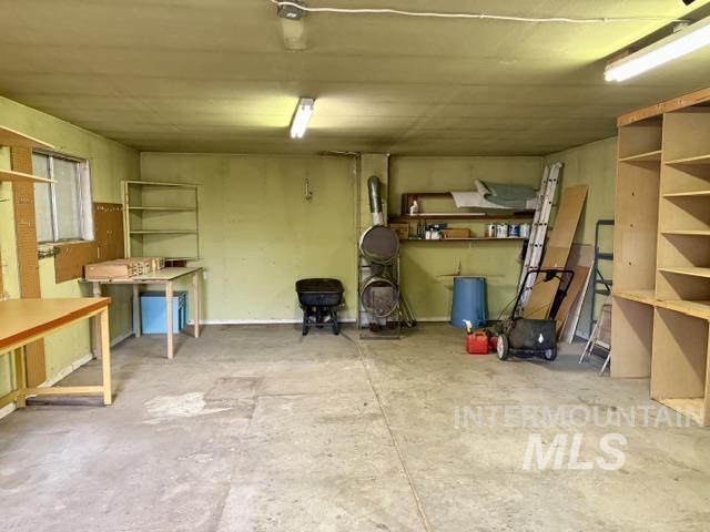 555 Cemetery Road Cambridge, ID 83610 - Photo 18 of 41 Concrete flooring with built-in shelving, a built-in work table, and a window