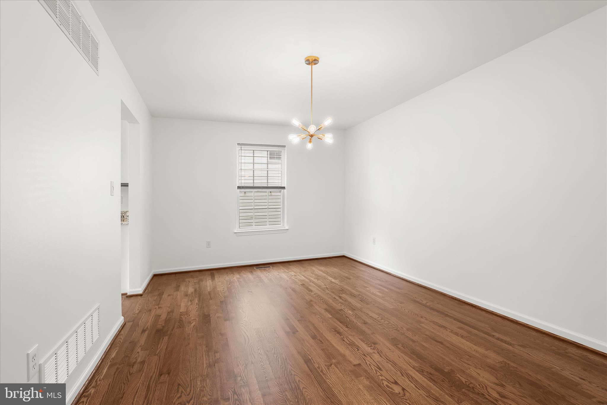 147 Idlewild Road Severna Park, MD 21146 - Photo 11 of 36 an empty room with wooden floor chandelier and windows