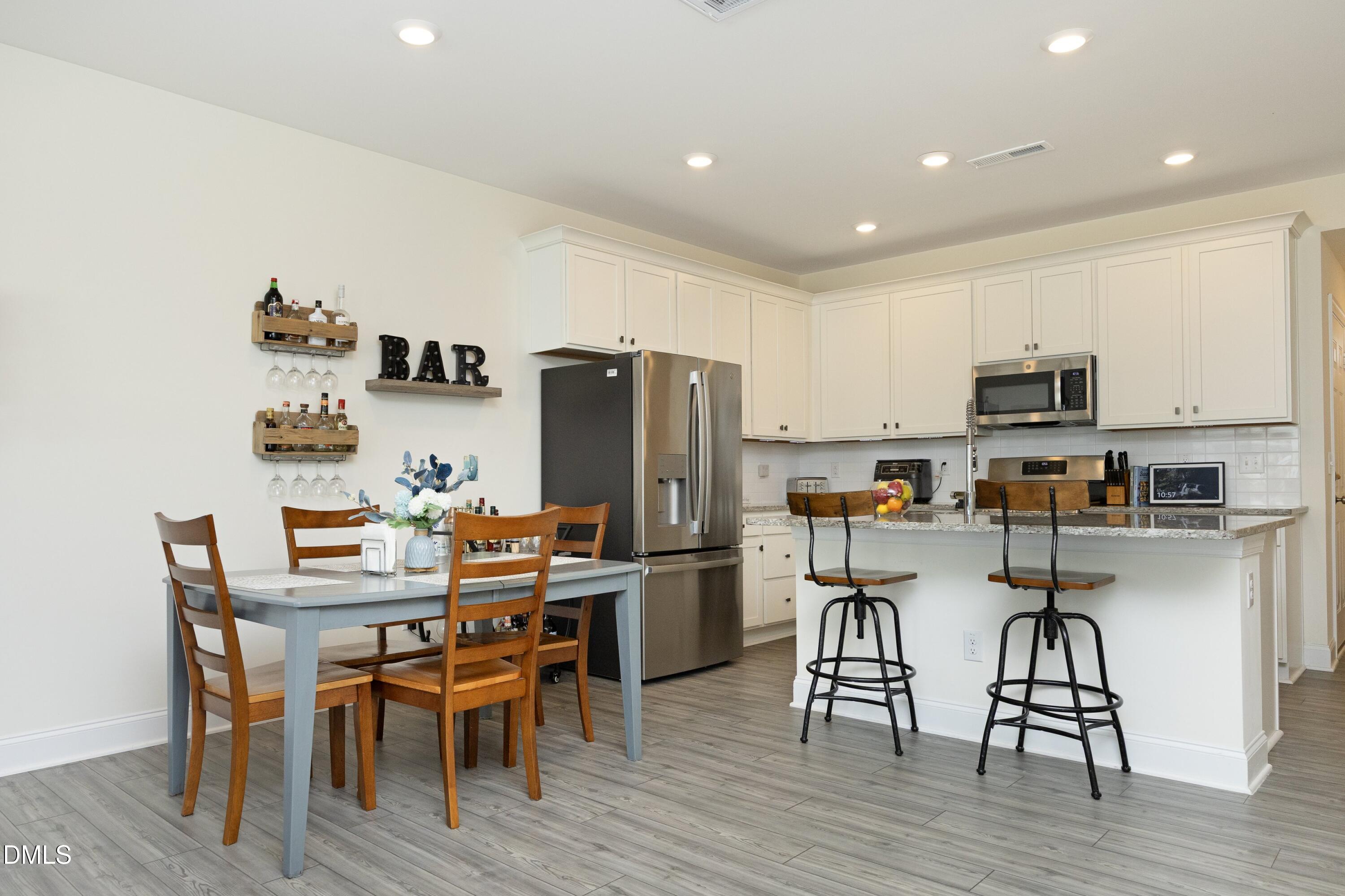 1002 Heartstone Way Durham, NC 27713 - Photo 5 of 35 a kitchen with stainless steel appliances a table chairs microwave and refrigerator
