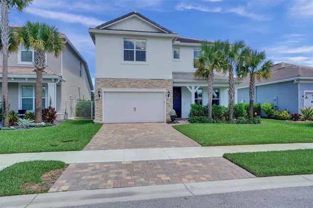 a front view of a house with a garden and palm trees