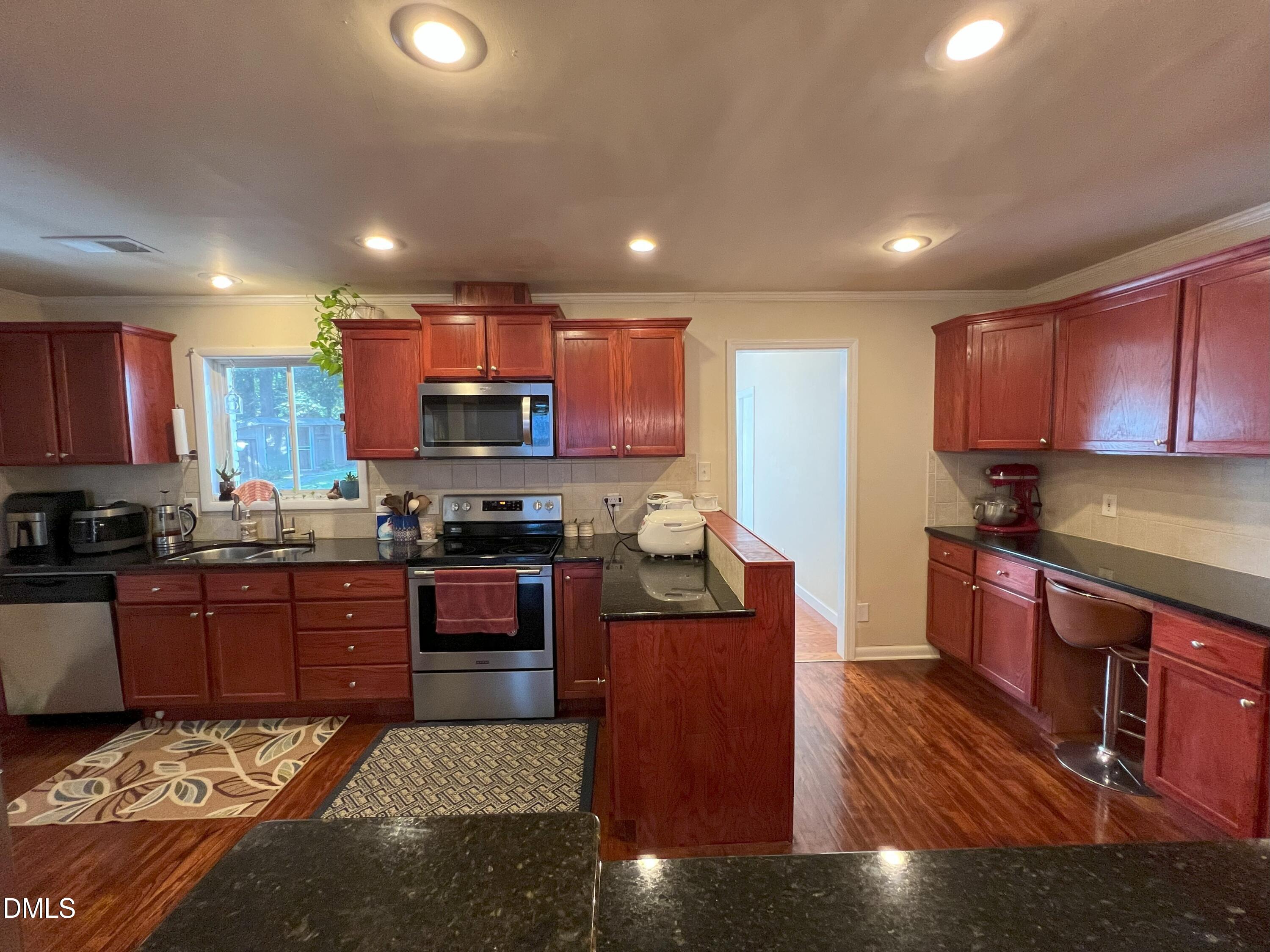 5002 Wickham Road Raleigh, NC 27606 - Photo 9 of 36 a kitchen with stainless steel appliances granite countertop a stove sink refrigerator and cabinets