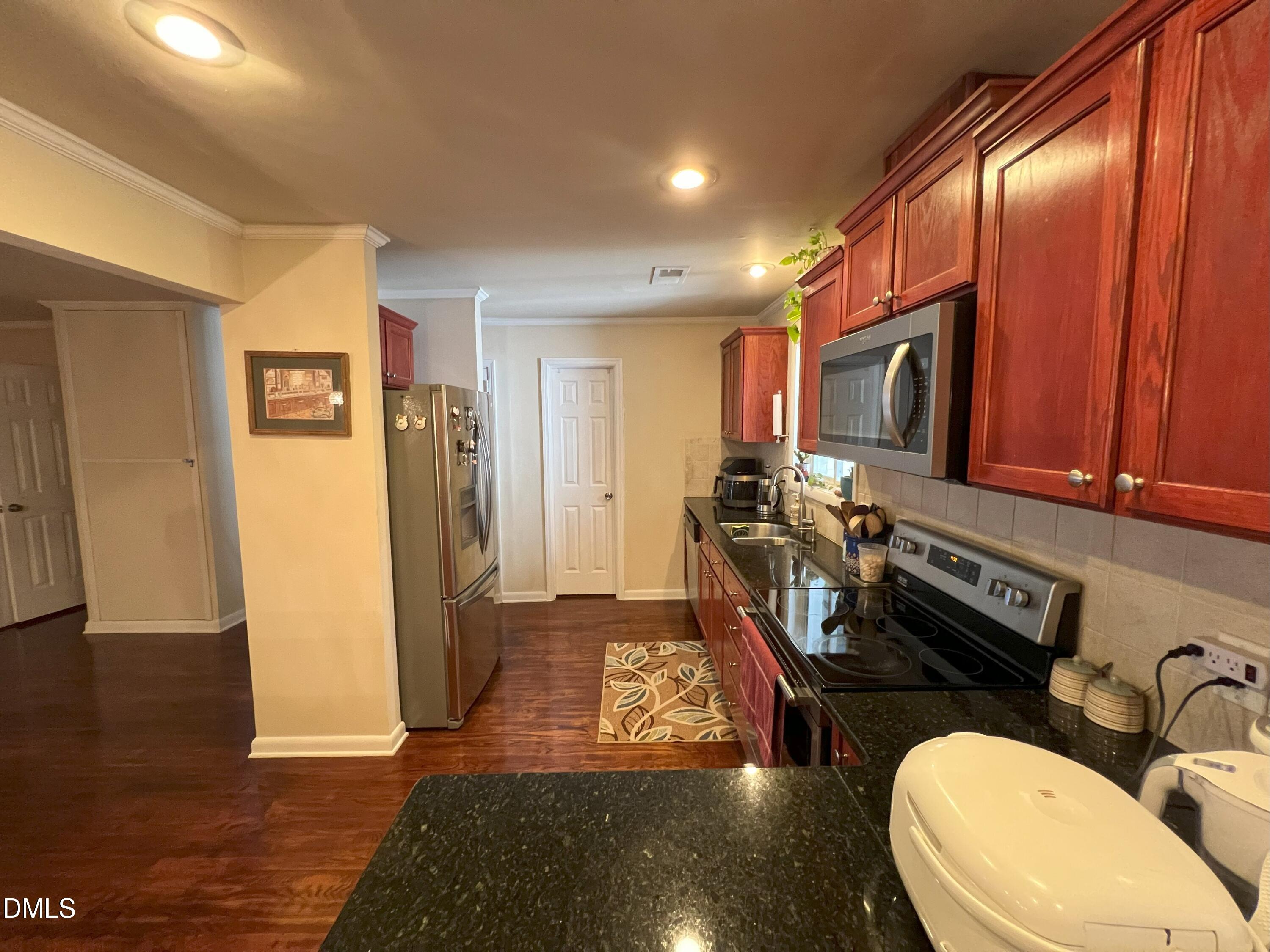 5002 Wickham Road Raleigh, NC 27606 - Photo 10 of 36 a view of a kitchen with a refrigerator a stove a sink and dishwasher with wooden floor