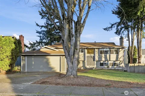 a front view of a house with a garden and trees