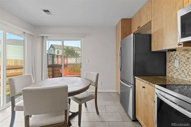 a kitchen with stainless steel appliances granite countertop a stove a refrigerator a table and chairs