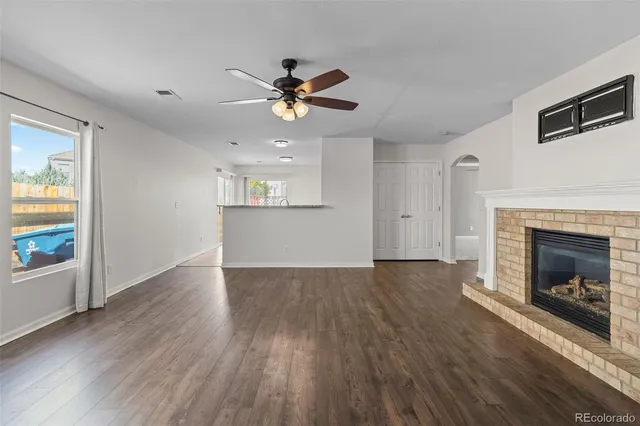 an empty room with wooden floor fireplace and windows