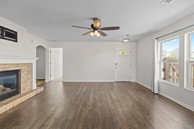 an empty room with wooden floor fireplace and windows