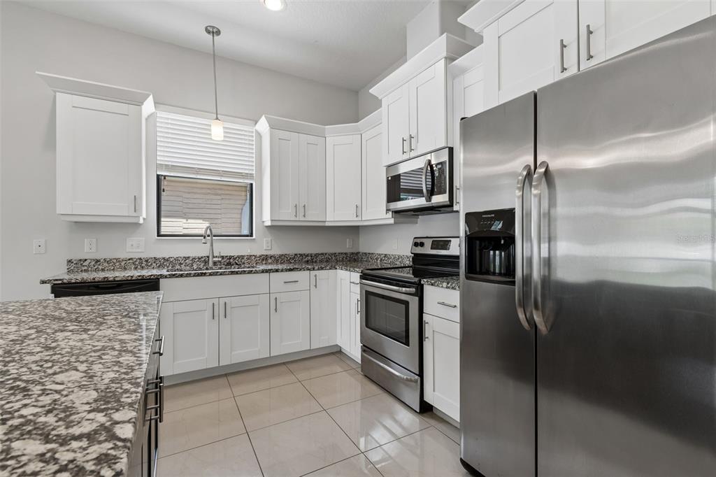 2311 West Aileen Street Tampa, FL 33607 - Photo 15 of 38 a kitchen with kitchen island granite countertop cabinets and stainless steel appliances