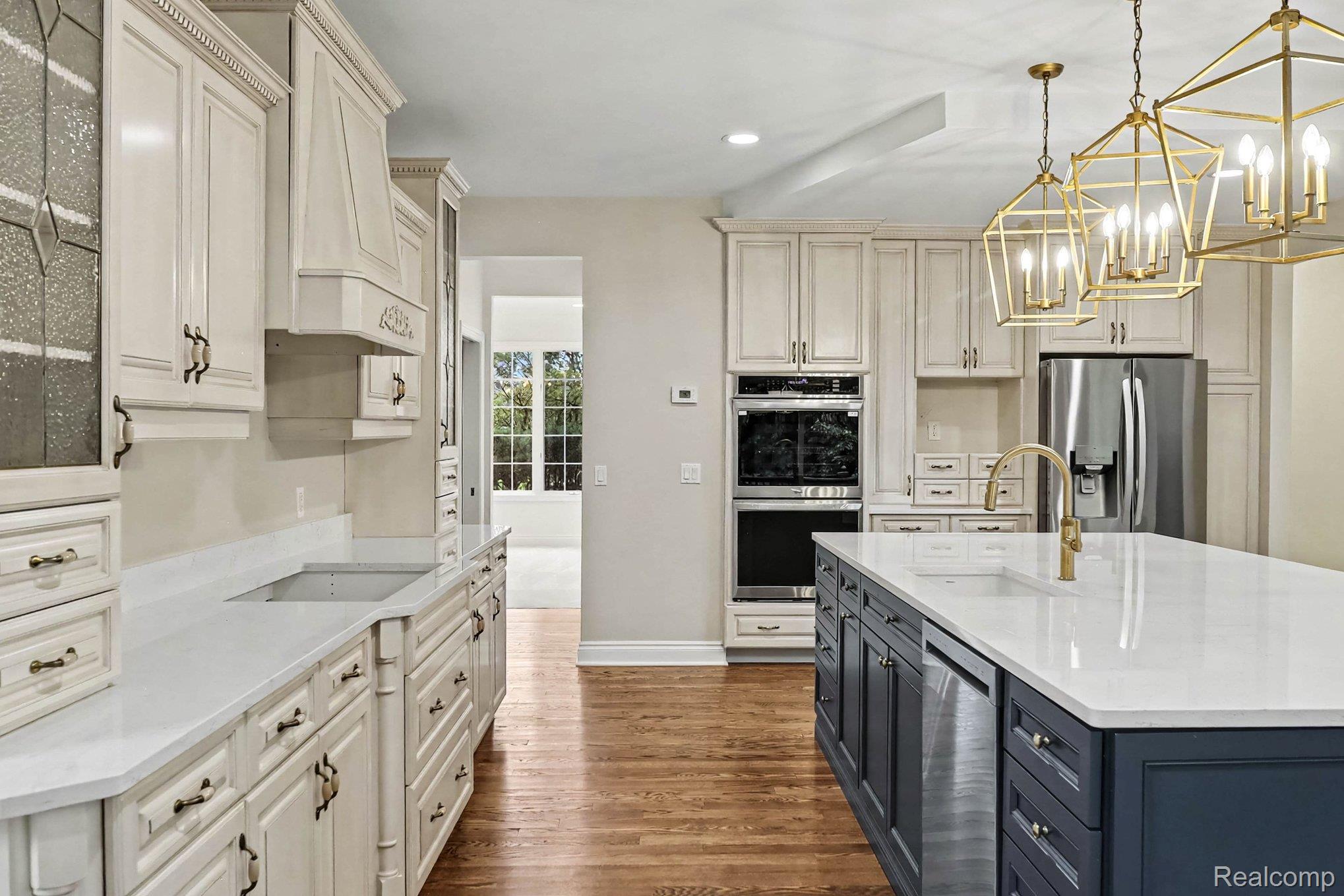 4875 Green Meadow Lane Rochester, MI 48306 - Photo 17 of 60 Hardwood flooring, painted cabinetry, stainless steel appliances, built-in double oven, and a kitchen island with sink