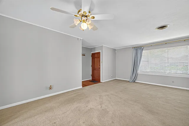 an empty room that has a mirror and a chandelier fan