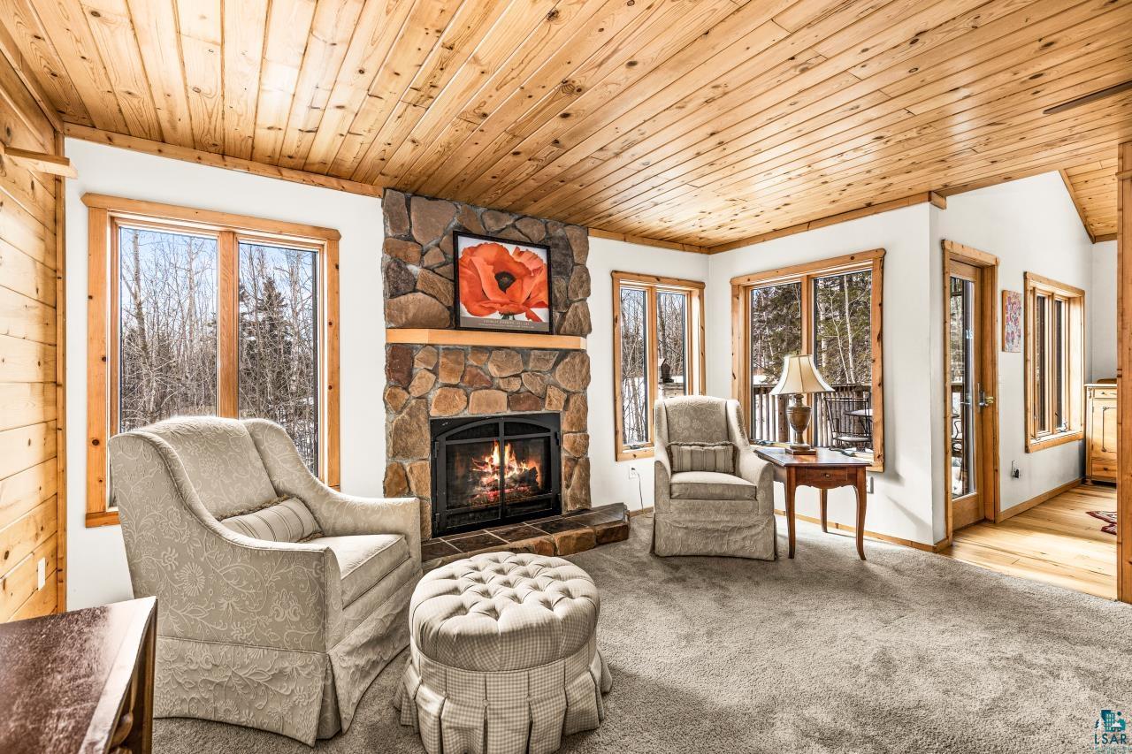 67 Snowshoe Trail Tofte, MN 55615 - Photo 11 of 42 Living area with wooden ceiling, carpet floors, healthy amount of natural light, and a fireplace
