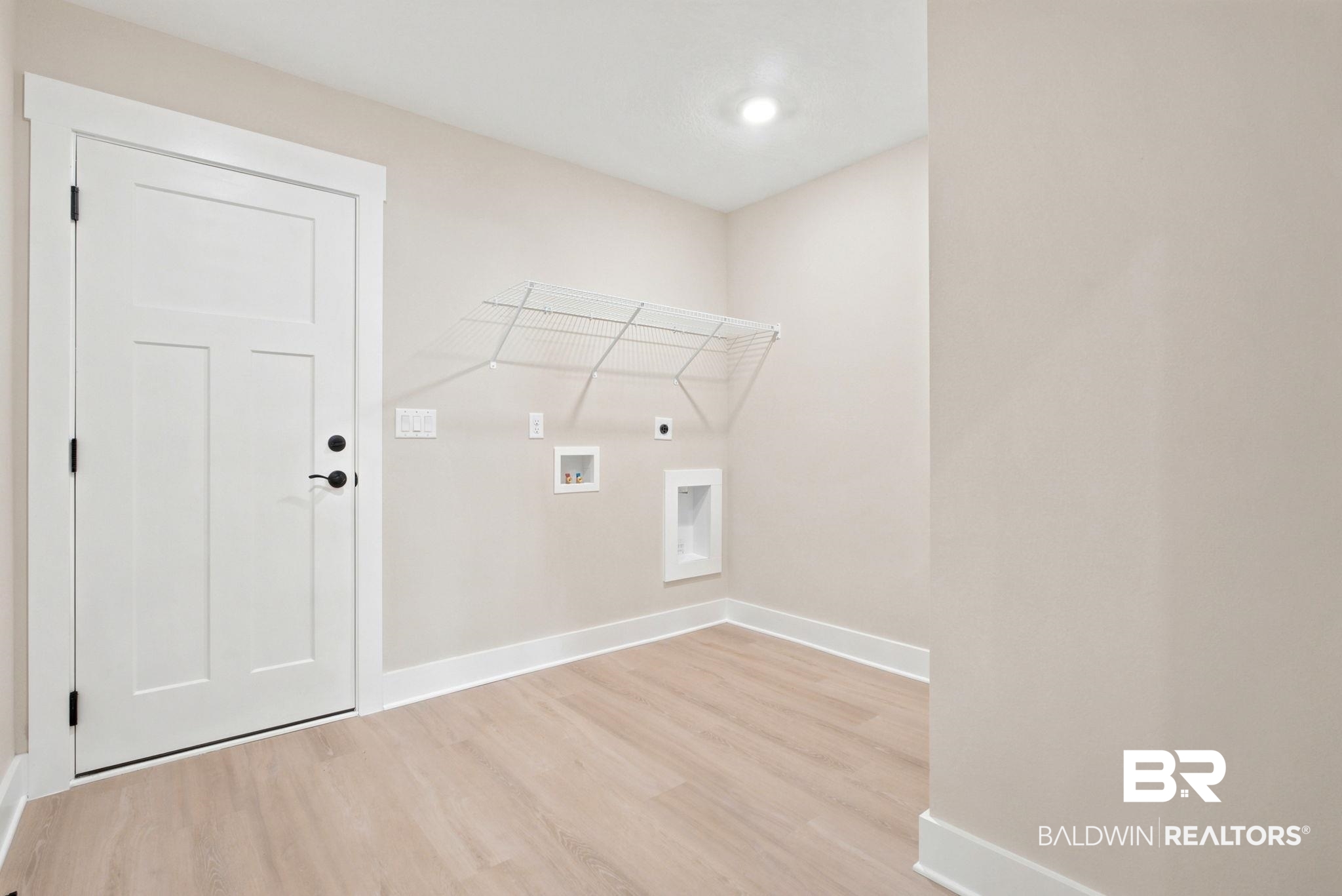 32656 Arbor Ridge Circle Lillian, AL 36549 - Photo 30 of 56 Utility space featuring light wood-finish flooring, white baseboards, and a three-panel interior door with matte black hardware