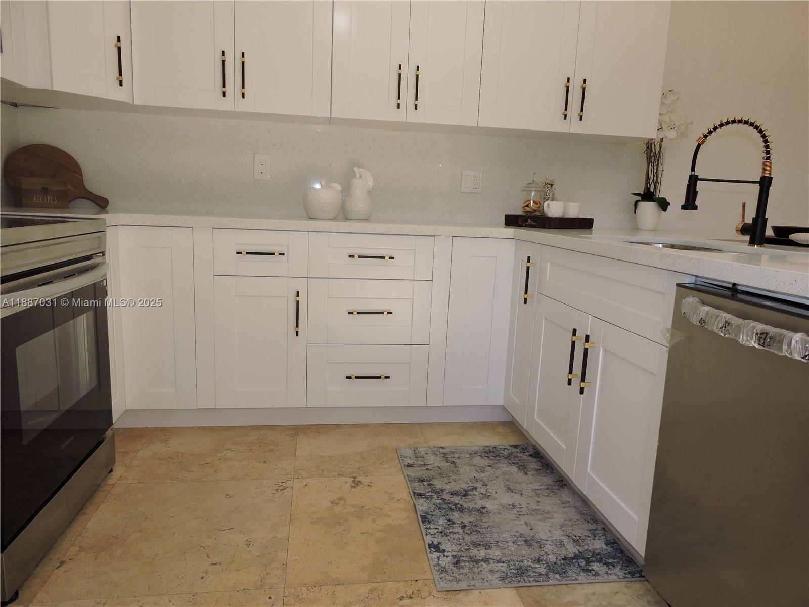 1316 Southwest 118th Terrace, Unit 1316 Davie, FL 33325 - Photo 13 of 44 a kitchen with white cabinets and sink