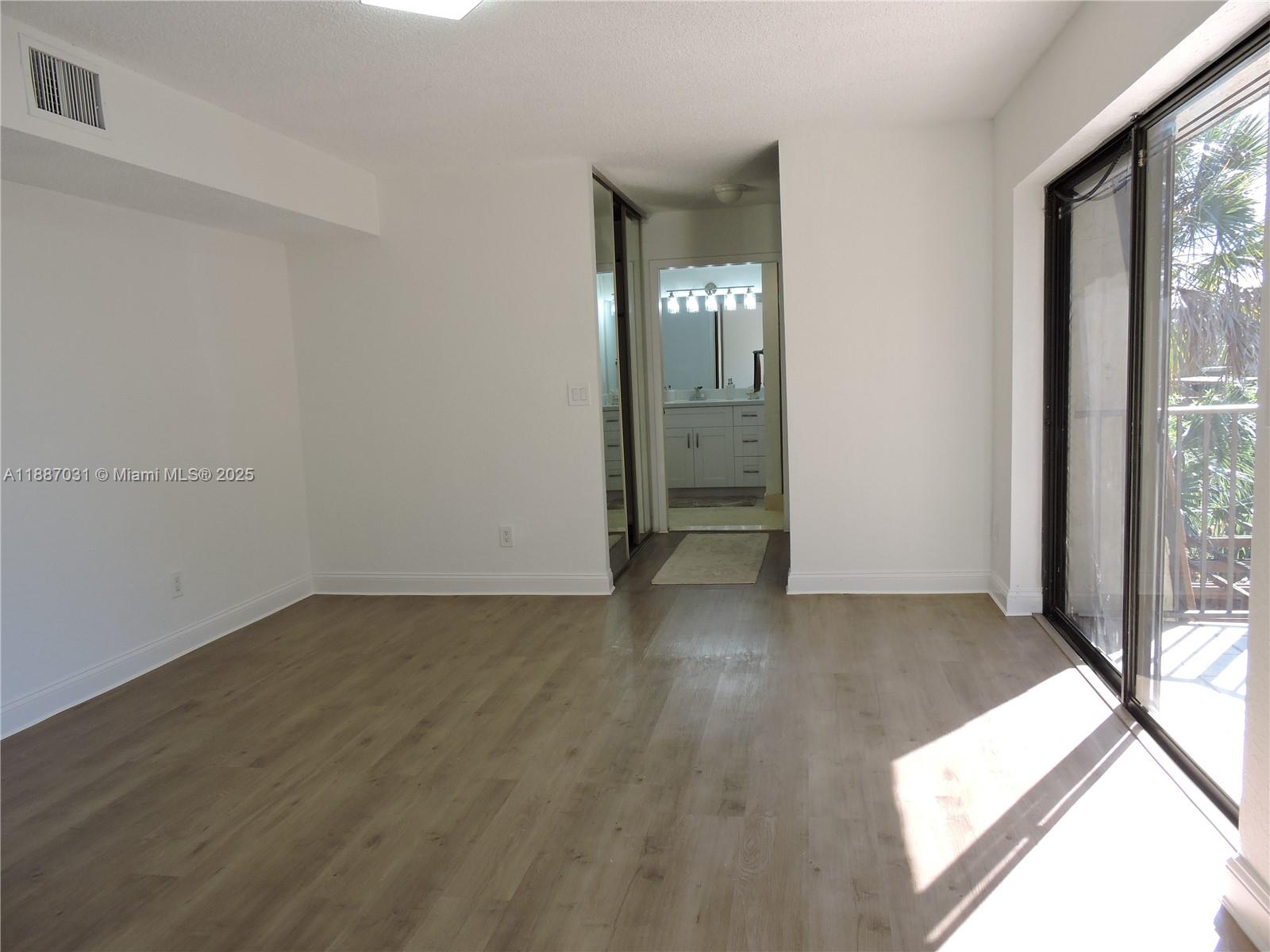 1316 Southwest 118th Terrace, Unit 1316 Davie, FL 33325 - Photo 34 of 44 an empty room with wooden floor and windows