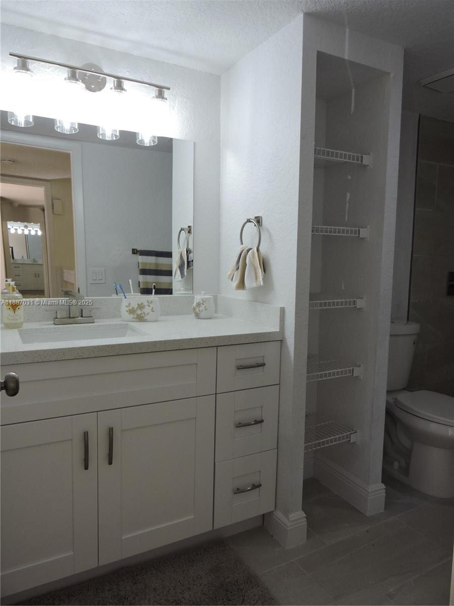 1316 Southwest 118th Terrace, Unit 1316 Davie, FL 33325 - Photo 40 of 44 a bathroom with a granite countertop sink vanity mirror and toilet