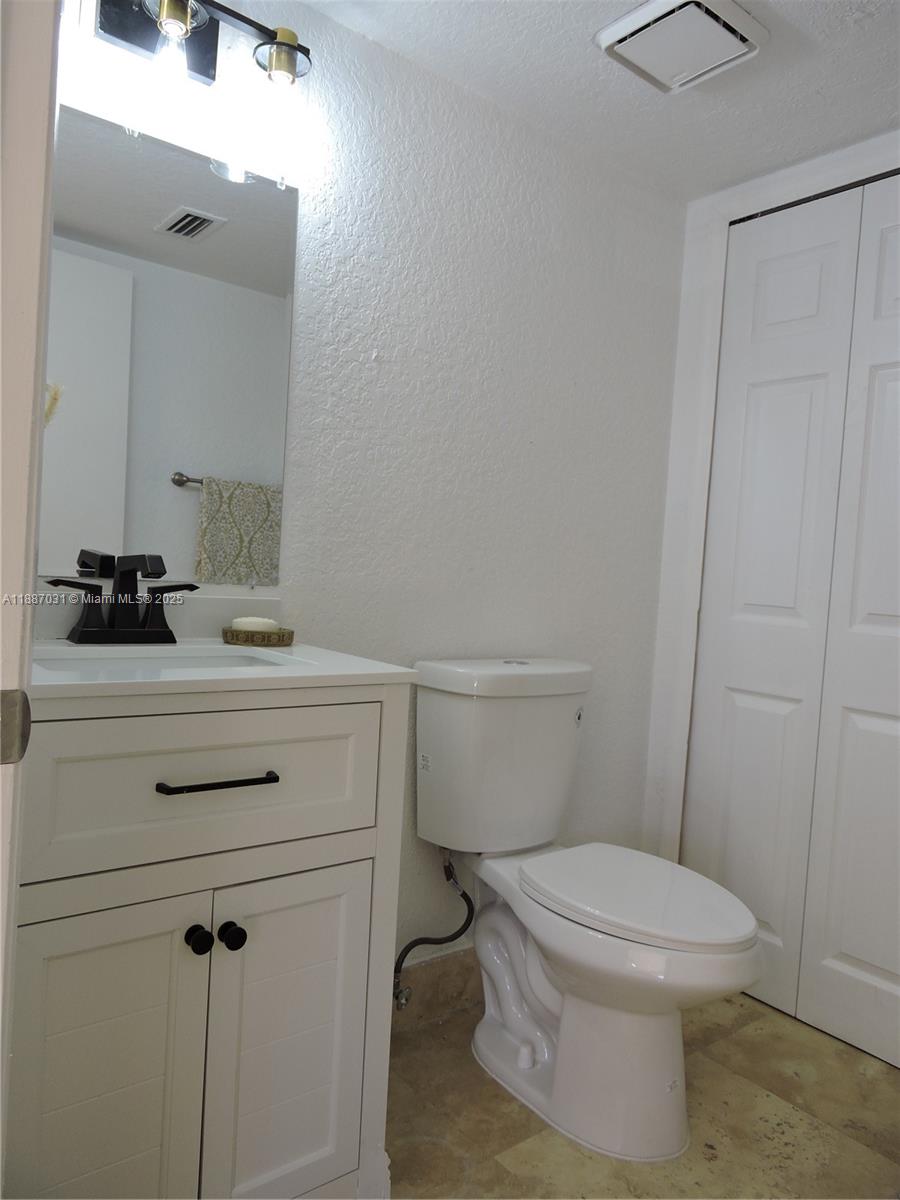 1316 Southwest 118th Terrace, Unit 1316 Davie, FL 33325 - Photo 44 of 44 a bathroom with a toilet a sink a vanity and mirror