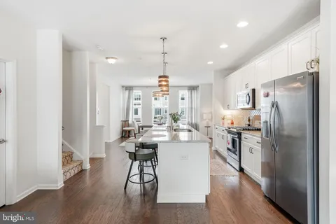 a kitchen with stainless steel appliances a dining table chairs stove and refrigerator