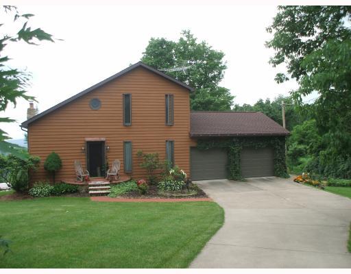 Exterior Front. The cedar siding on the front has been replaced with concrete siding(looks exactly like cedar)  Notice the level concrete driveway and manicured lawn and flower beds.