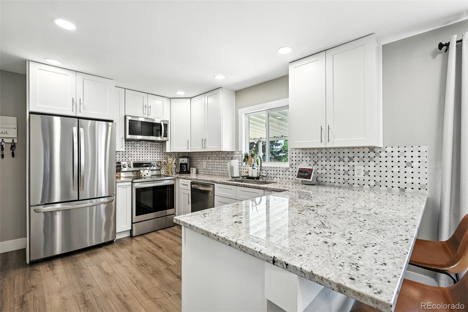 2714 South Raleigh Street Denver, CO 80236 - Photo 9 of 34 a kitchen with granite countertop white cabinets and stainless steel appliances
