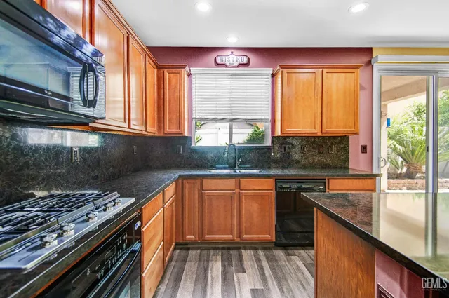 a kitchen with stainless steel appliances granite countertop a stove a sink and a microwave