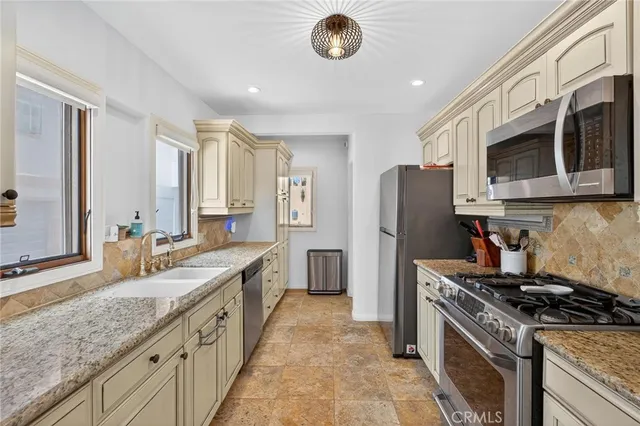 a kitchen with stainless steel appliances granite countertop a stove a sink and a refrigerator