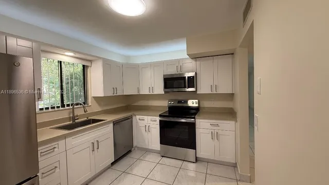 a kitchen with a sink white cabinets and appliances