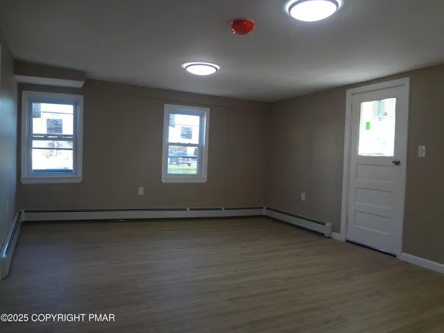 an empty room with wooden floor and windows